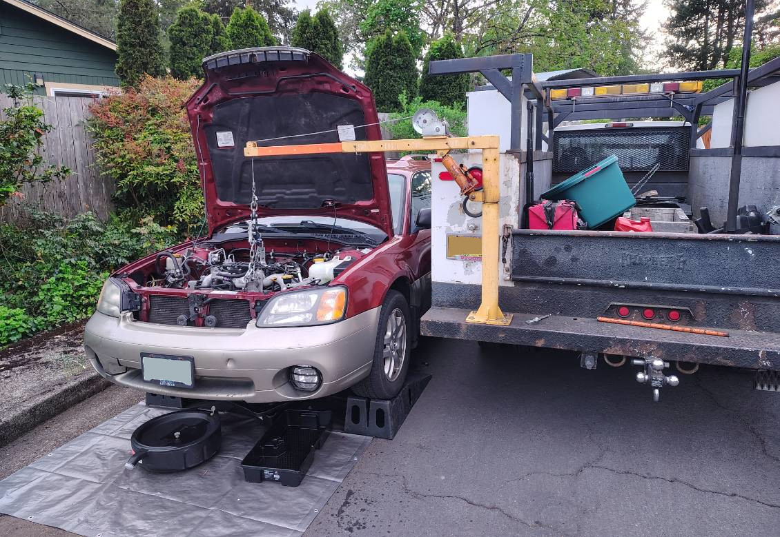 Engine work being done on a red car, using a hoist from AJ's truck.